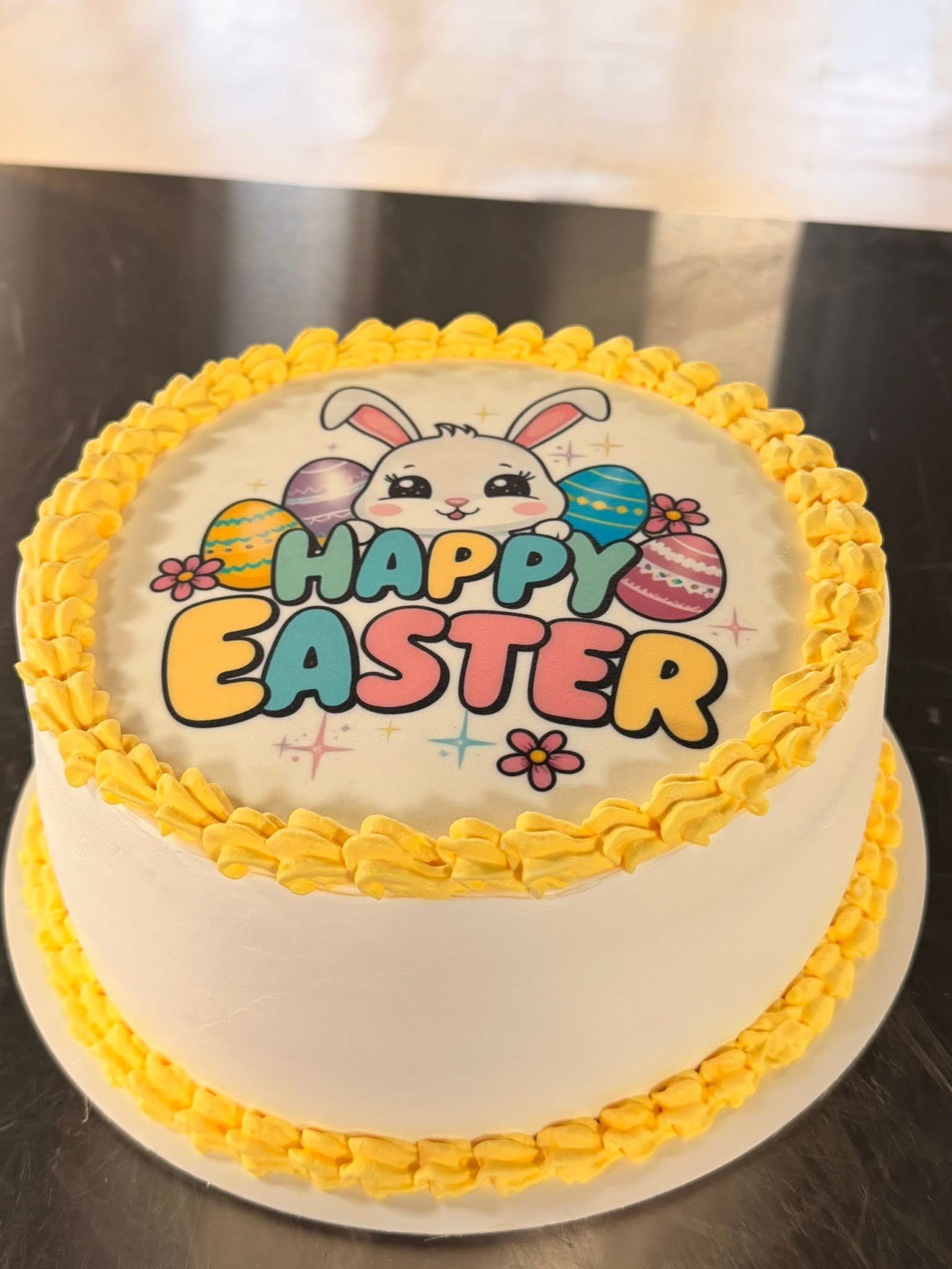 Easter themed round cake decorated with a rabbit and yellow frosting border