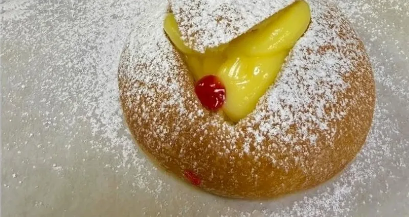 Soft sweet roll filled with custard cream and topped with a cherry