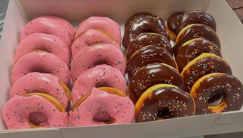 Box of fresh pink and chocolate glazed sprinkle donuts
