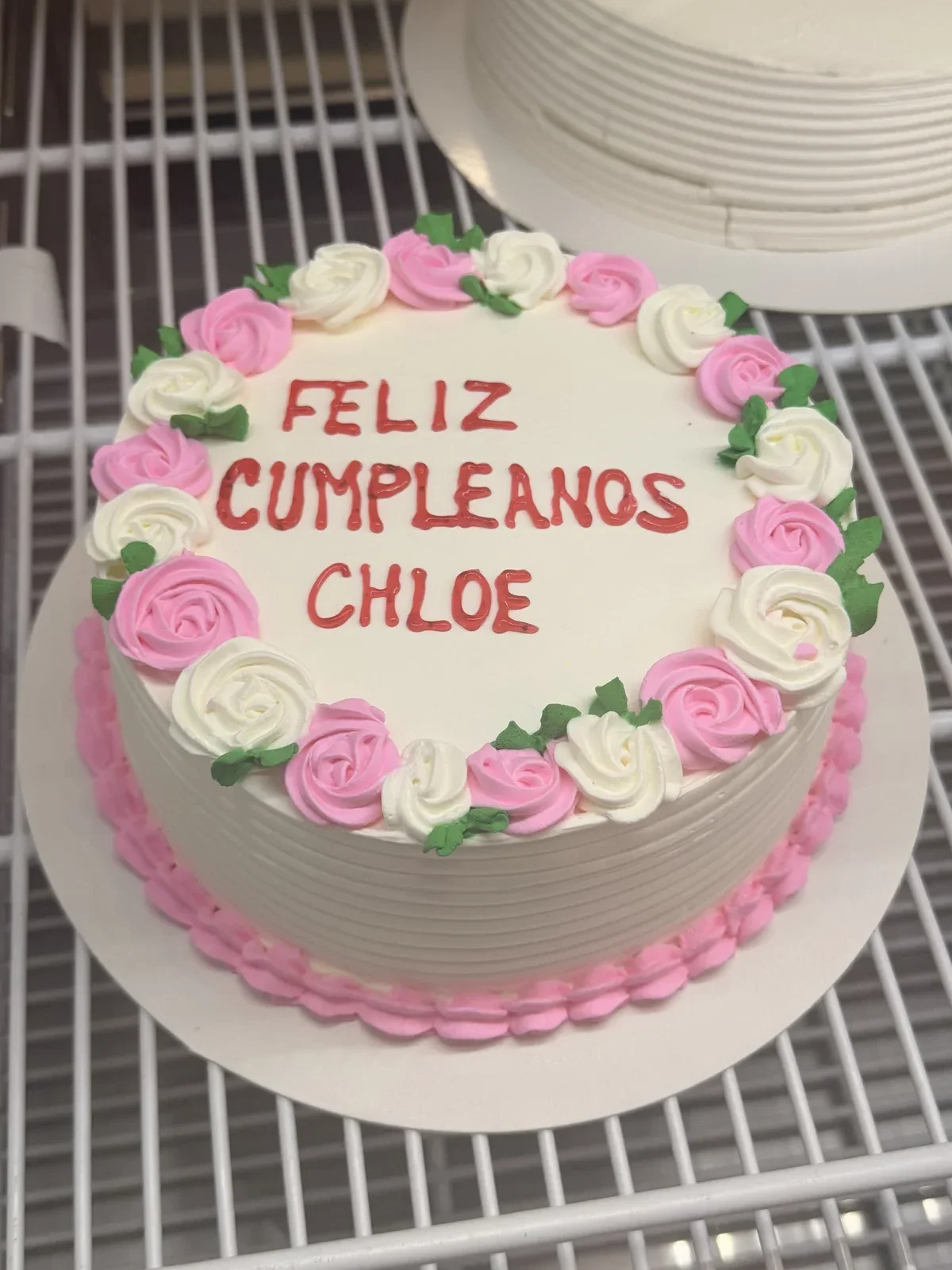 Custom celebration cake with pink and white roses and Feliz Cumpleaños Chloe message